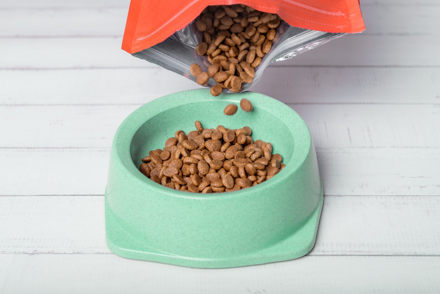 Pet food being poured into a cat food bowl